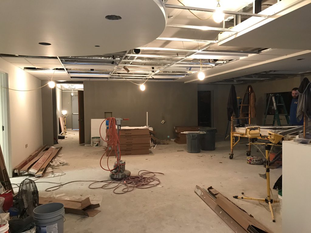 view of painted walls from new entry way of lobby, worker and construction materials.