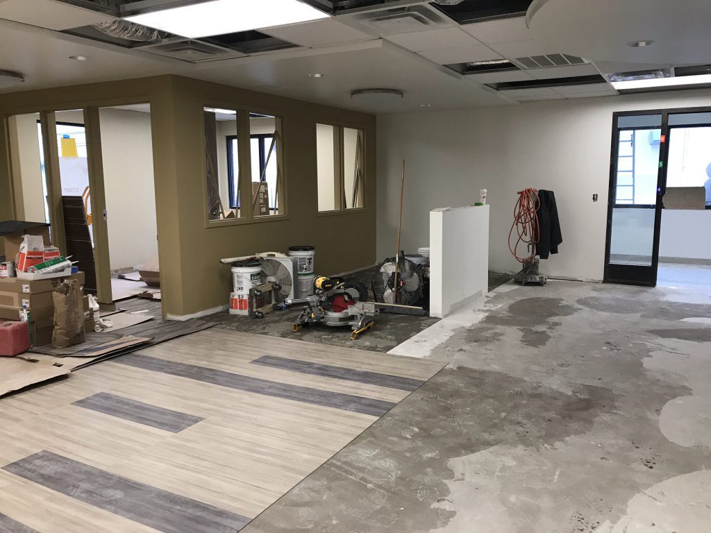 New waiting area with flooring being installed. New office painted with boxes of flooring.