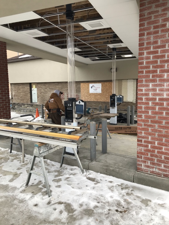 Drive-thru with new video monitors; worker installing equipment.